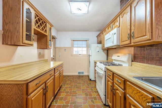 kitchen with backsplash, white appliances, and sink