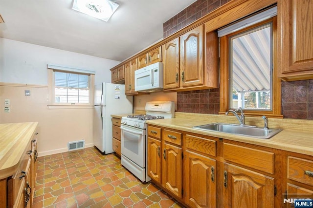 kitchen featuring white appliances, sink, decorative backsplash, and a wealth of natural light