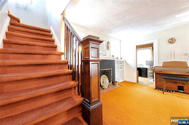 stairs with a brick fireplace and carpet flooring