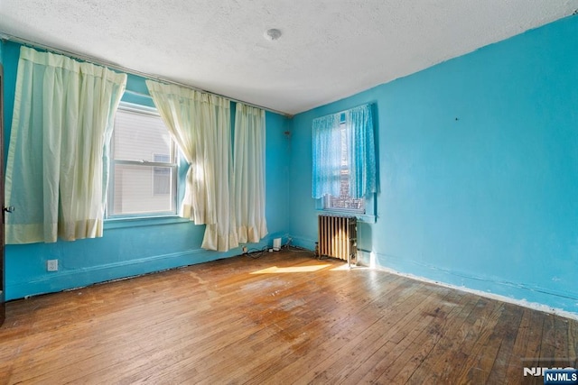 empty room with hardwood / wood-style flooring, radiator heating unit, and a textured ceiling