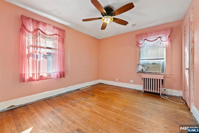 spare room with light hardwood / wood-style flooring, cooling unit, a wealth of natural light, and radiator heating unit