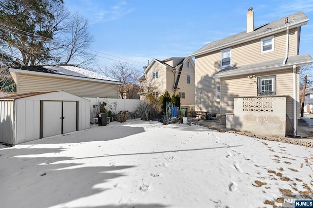 snow covered back of property with a storage unit