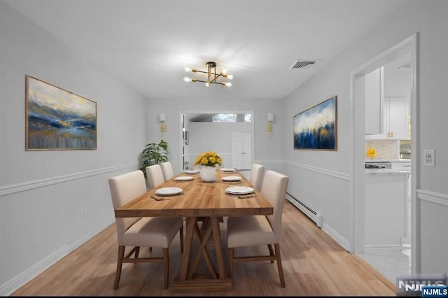 dining area with baseboard heating, light hardwood / wood-style floors, and an inviting chandelier