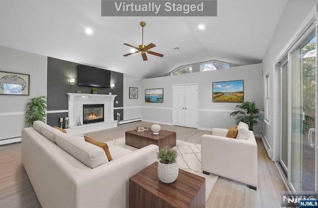 living room with vaulted ceiling, plenty of natural light, and light hardwood / wood-style flooring