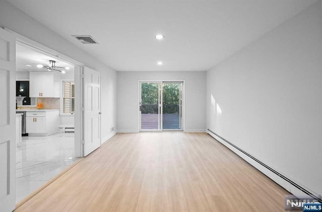 unfurnished room featuring a baseboard heating unit and light hardwood / wood-style floors