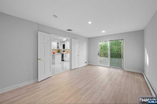 unfurnished living room with light hardwood / wood-style flooring and baseboard heating