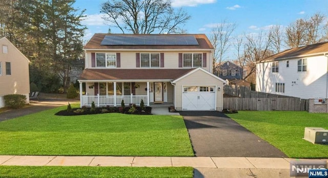 view of front of house featuring a front yard, covered porch, and solar panels