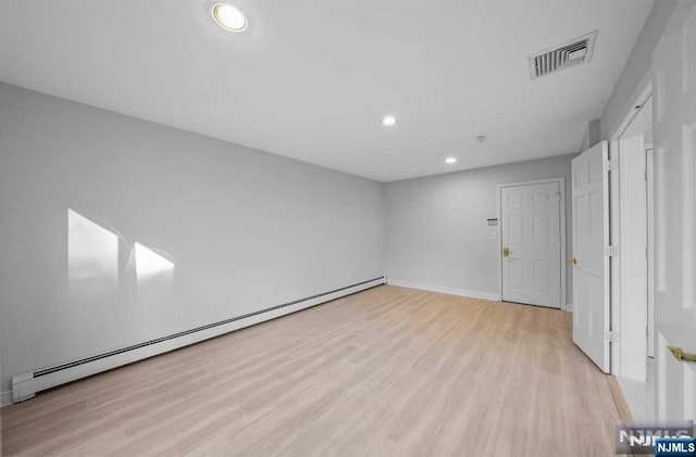 unfurnished room featuring a baseboard radiator and light hardwood / wood-style floors