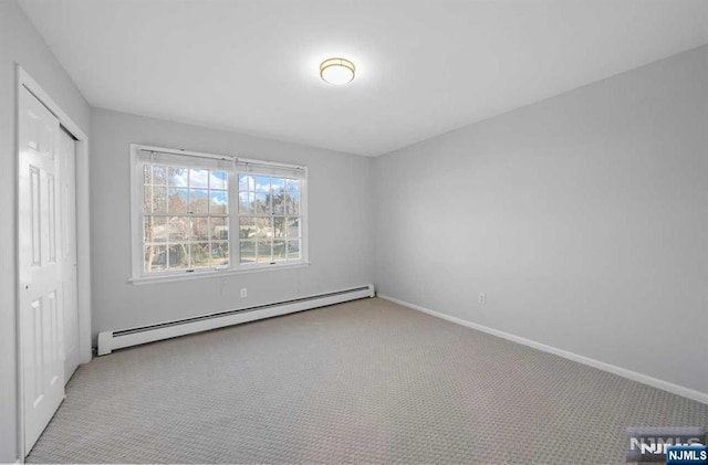 unfurnished bedroom featuring light carpet, a baseboard heating unit, and a closet