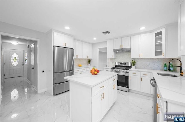 kitchen featuring sink, white cabinets, decorative backsplash, a center island, and stainless steel appliances