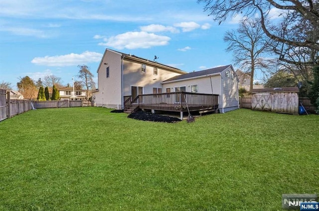 rear view of house with a wooden deck and a lawn