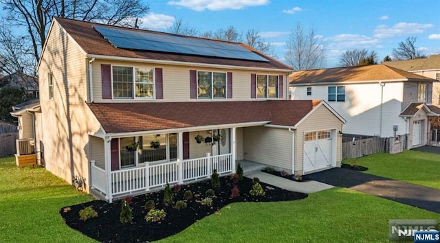 view of front of house with a porch, central AC unit, a front lawn, and solar panels