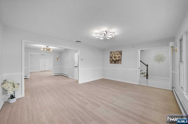 spare room featuring light hardwood / wood-style flooring, a baseboard radiator, and an inviting chandelier