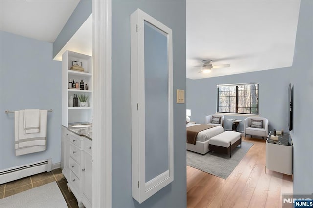 bedroom with baseboard heating, ceiling fan, and hardwood / wood-style flooring