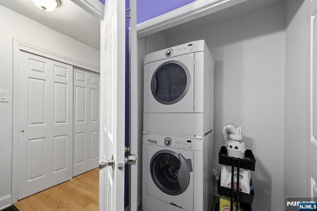 washroom featuring hardwood / wood-style flooring and stacked washer and clothes dryer