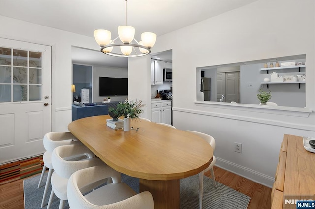 dining space with wood-type flooring and an inviting chandelier