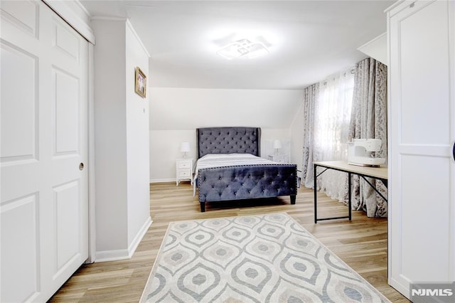 bedroom with lofted ceiling and light wood-type flooring