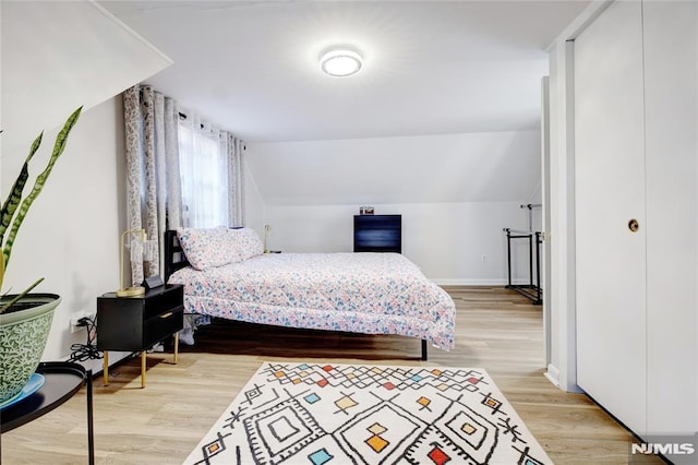 bedroom with lofted ceiling and light wood-type flooring