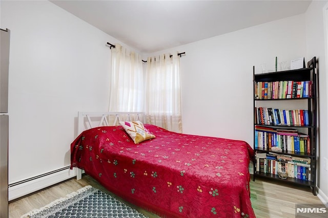 bedroom with baseboard heating and wood-type flooring