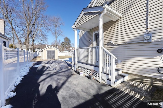 snow covered property with a storage shed and a patio area