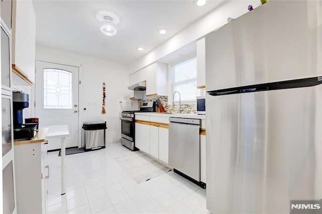 kitchen with stainless steel appliances, sink, decorative backsplash, and white cabinets