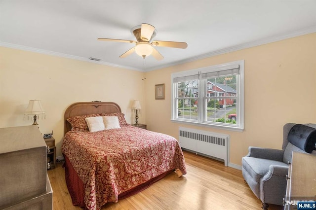 bedroom with crown molding, radiator heating unit, ceiling fan, and light wood-type flooring