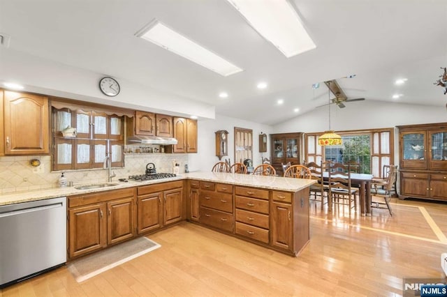 kitchen featuring sink, hanging light fixtures, light wood-type flooring, appliances with stainless steel finishes, and kitchen peninsula