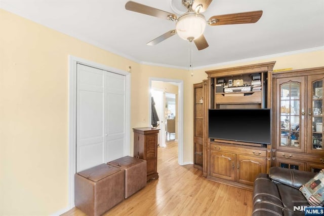 living room featuring crown molding, ceiling fan, and light wood-type flooring