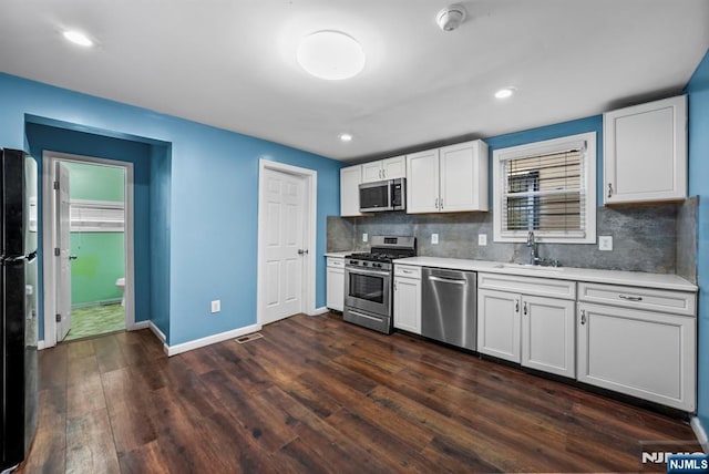 kitchen with sink, tasteful backsplash, appliances with stainless steel finishes, dark hardwood / wood-style flooring, and white cabinets