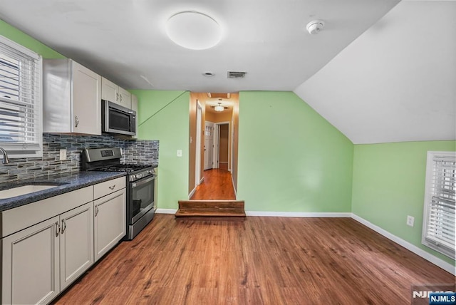 kitchen with sink, white cabinetry, wood-type flooring, appliances with stainless steel finishes, and decorative backsplash