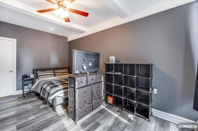 bedroom with baseboards, beam ceiling, and wood finished floors