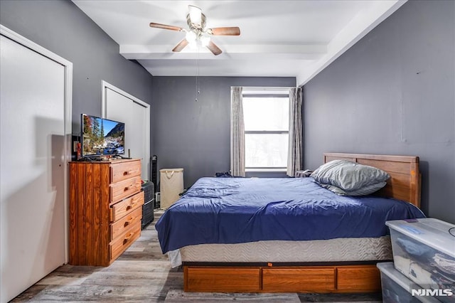 bedroom featuring light wood finished floors, beamed ceiling, and a ceiling fan