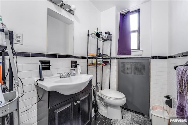 bathroom with radiator, toilet, tile walls, and wainscoting