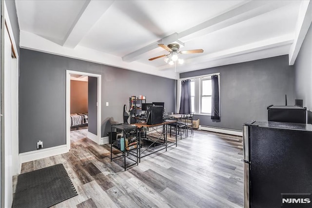 office space featuring ceiling fan, a baseboard radiator, wood finished floors, baseboards, and beamed ceiling