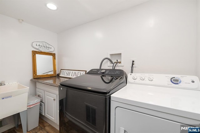 clothes washing area with independent washer and dryer, sink, wood-type flooring, and cabinets