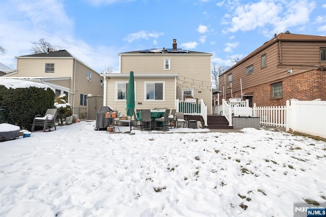 snow covered back of property with a wooden deck