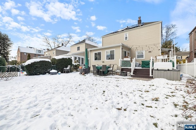 snow covered property with a wooden deck and solar panels