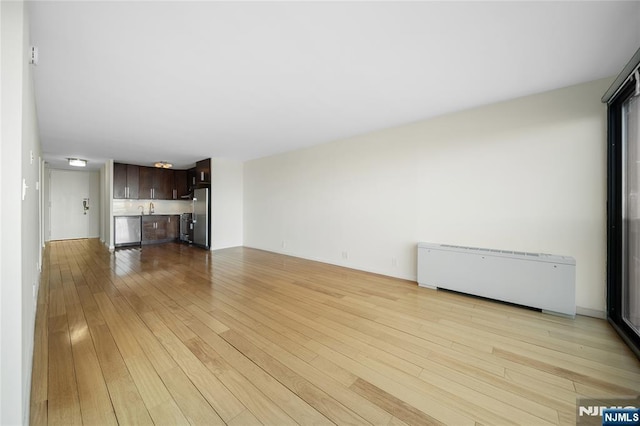 unfurnished living room with radiator and light wood finished floors