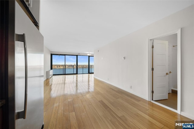 interior space with light wood-type flooring, baseboards, and floor to ceiling windows