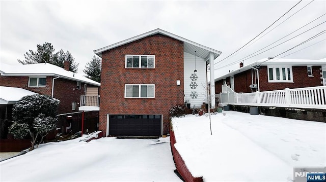 snow covered back of property featuring a garage