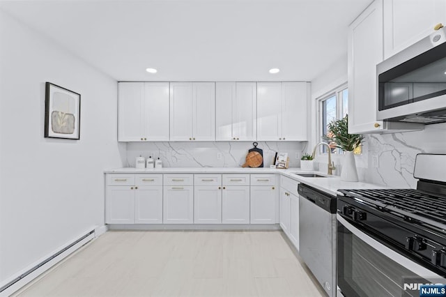 kitchen with appliances with stainless steel finishes, a baseboard heating unit, sink, and white cabinets