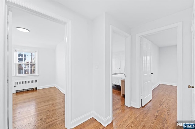 hallway featuring radiator heating unit and light hardwood / wood-style floors