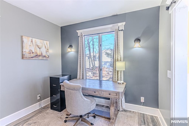 home office featuring a barn door and light hardwood / wood-style floors