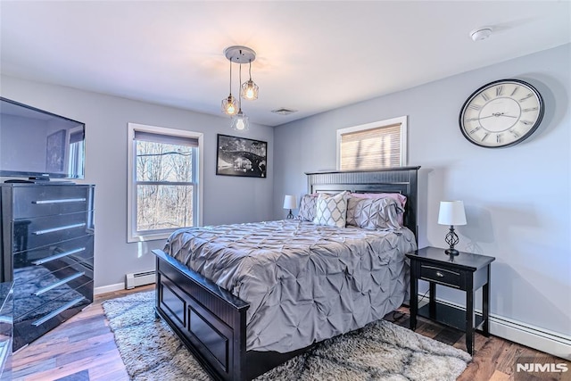 bedroom with a baseboard radiator and wood-type flooring