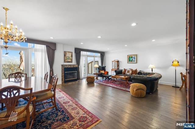 living room featuring a notable chandelier, dark wood-type flooring, and a tile fireplace