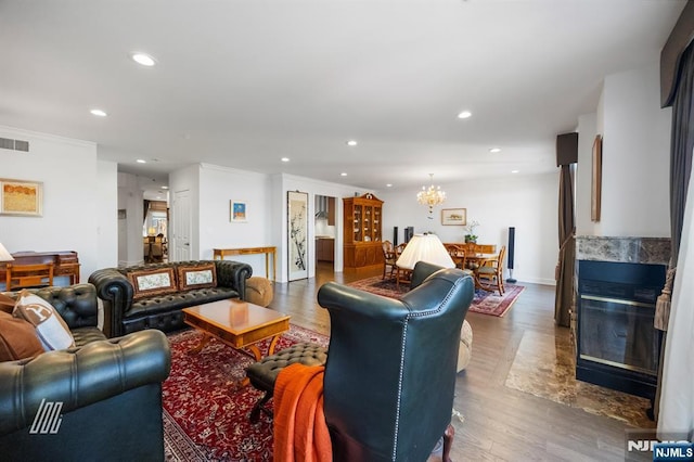 living room with an inviting chandelier, crown molding, a premium fireplace, and hardwood / wood-style flooring