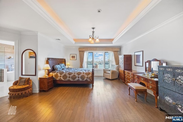 bedroom featuring crown molding, wood-type flooring, a tray ceiling, and a chandelier