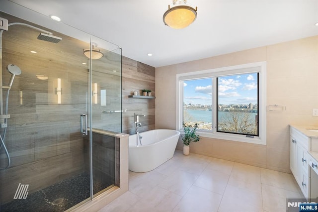 bathroom featuring tile walls, tile patterned flooring, a water view, vanity, and separate shower and tub