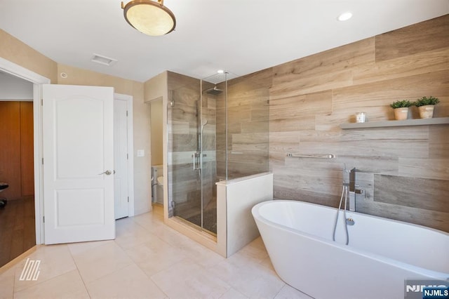 bathroom with tile patterned floors, plus walk in shower, and tile walls