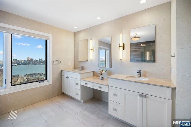 bathroom featuring a water view, tile patterned floors, vanity, and tile walls